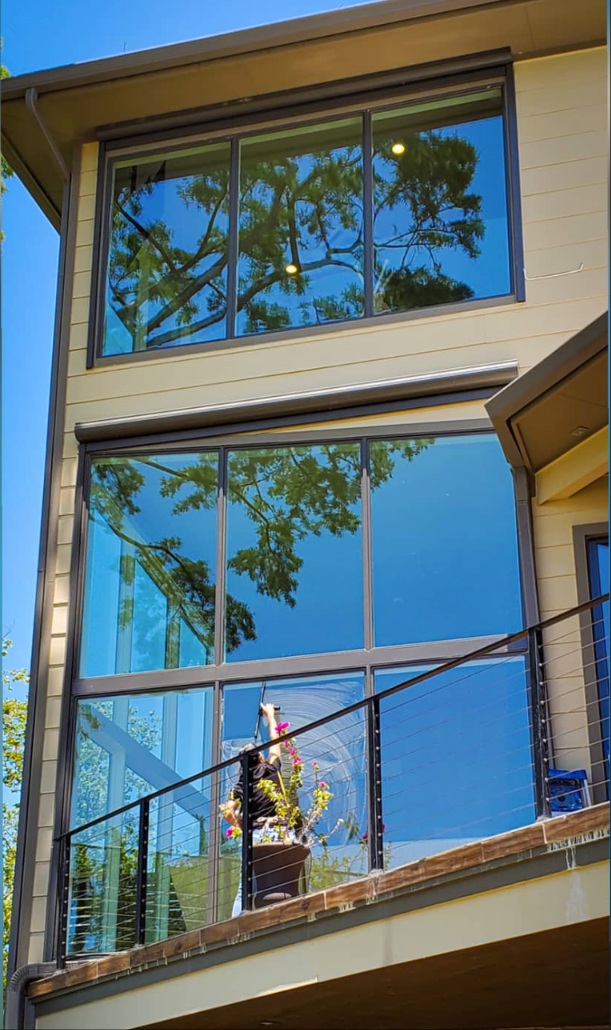 Two-story glass wall being cleaned above a balcony